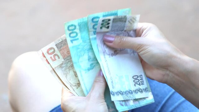 Woman holds some fifty, one hundred and two hundred reais notes, Brazilian money. According to official data, the average household income per capita (per person) increased in Brazil