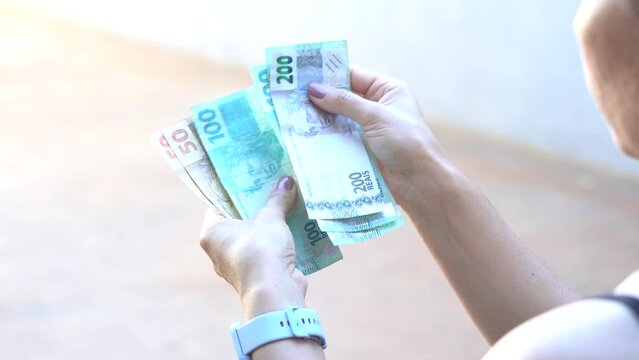 Woman holds some fifty, one hundred and two hundred reais notes, Brazilian money. According to official data, the average household income per capita (per person) increased in Brazil