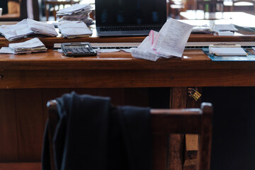 messy office with paper receipts and a  laptop