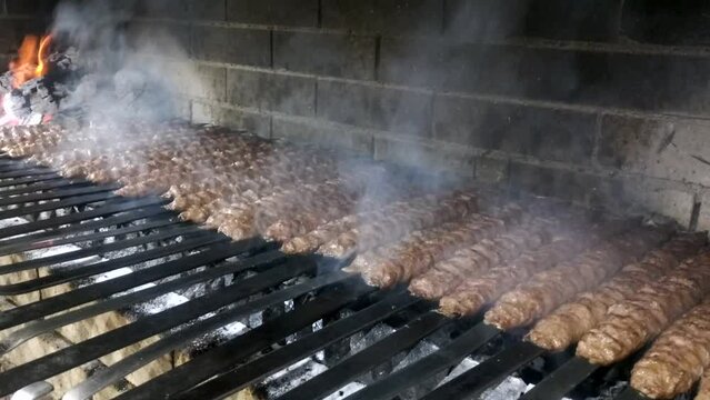 A dish of oriental cuisine, lula kebab, is fried over coals on the grill. Meat juice falls onto the hot coals and thick aromatic smoke comes out. delicious food for children and adults