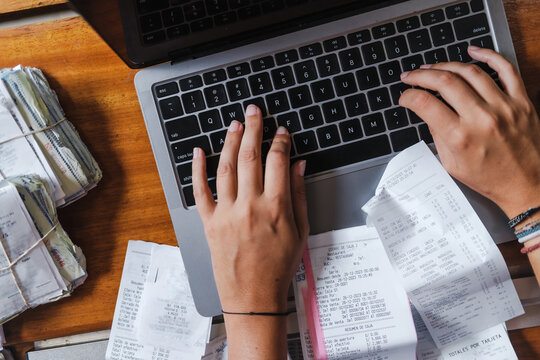 recepits and an unrecognizable woman working on her laptop