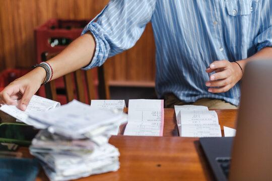 unrecognizable woman tackling a mountain of paperwork and receipts