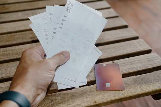 Bunch or receipts on the table with hand and credit card