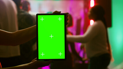 Girl showing greenscreen display at club holding blank chroma key display at party on dance floor....