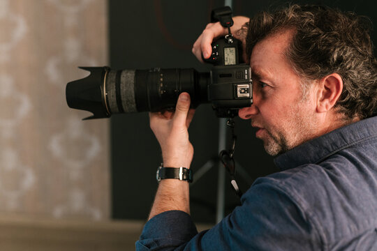 Professional male photographer taking photo on camera in studio