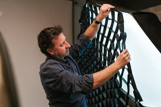 Man photographer putting grid on softbox in studio
