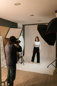 Man photographing model in modern photo studio