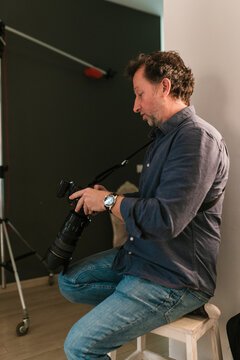 Focused man photographer checking photo camera lens