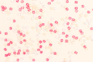 Texture made from shiny acrylic beads scattered on a beige background.