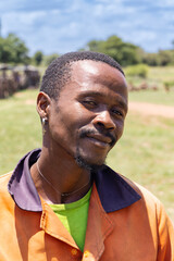 village young african man with a smile wearing orange workwear in the field in a summer day
