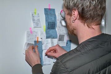 Young man checking receipts on the wall