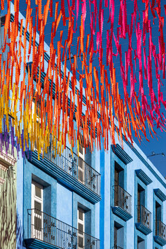 Colorful paper hanging from the sky next to a blue building