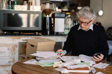 Senior Businessman Multitasking with Documents and Phone

