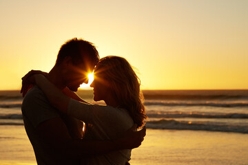 Couple, love and kiss at beach with sunset for date or summer holiday and bonding in Florida....