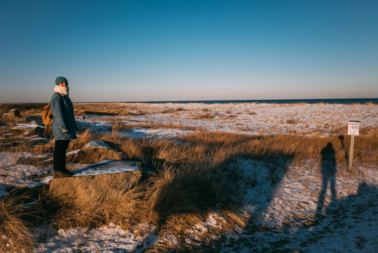 Person on Snowy Beach with No Pets Sign and photographer's shadow