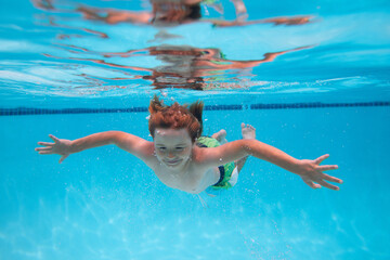 Young boy swim and dive underwater. Under water portrait in swim pool. Child boy diving into a swimming pool. Beach sea and water fun.