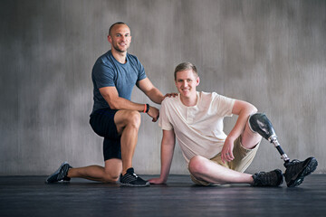 Trainer, person with a disability and prosthetic leg and posing in physiotherapy, studio and workout. Male people, physiotherapist and amputee for wellness, fitness and exercise in sports center