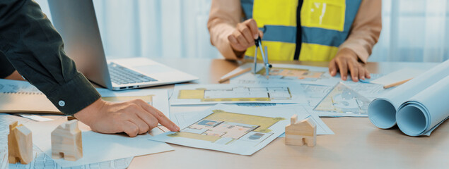 Skilled engineer uses divider to measure the blueprint while architect pointing the mistake point...