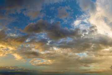 Naklejka na ściany i meble Dramatic sunset sky covered with colorful yellow clouds. Panoramic skyscape