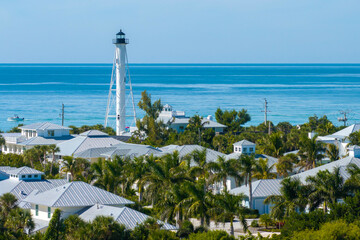 Expensive waterfront houses and white Boca Grande lighthouse on ocean shore. Small town on Gasparilla Island in southwest Florida. Premium housing development in the USA