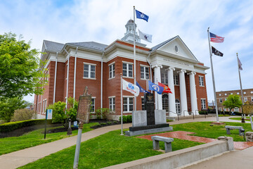 Numerous flags flutter proudly in front of a governmental edifice within a quaint rural town in the...