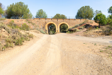 Camino del Sur - Via Verde de Riotinto - dirt road passing beneath a stone bridge near Zalamea la Real, province of Huelva, Andalusia, Spain