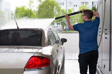Man washing his car with high pressure water. Car wash concept.Cleaning car with high pressure water