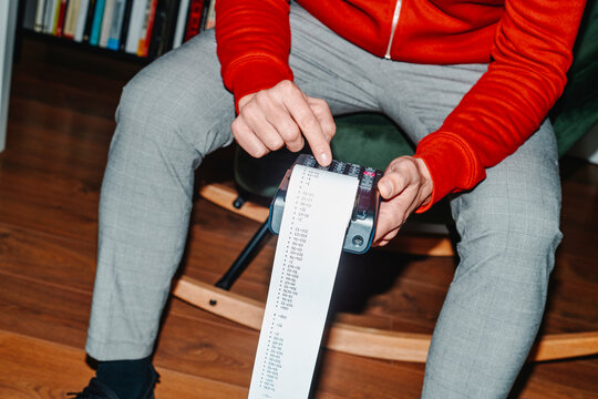 man sitting on a rocking chair uses an electronic calculator