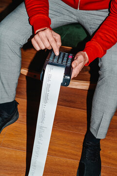 man wearing a red sweater using an electronic calculator