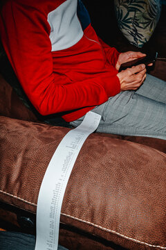 man sitting on the sofa with a long strip of paper with calculations