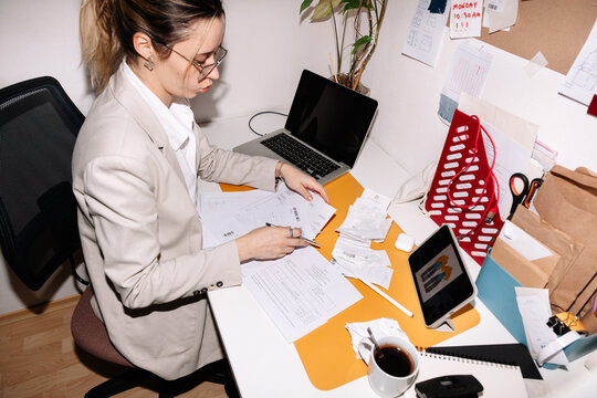Focused woman working on laptop and counting receipts