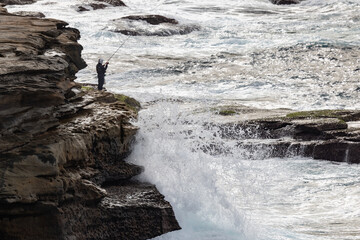 Fiherman fishing from rocks in dangerous sea