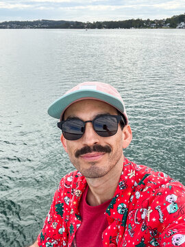 Selfie of a man with mustache wearing a Christmas shirt on a lake