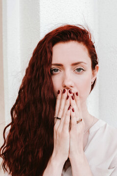 Portrait of a ginger woman hides her mouth with face