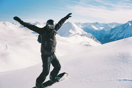 Young man on snowboard opposite the mountains