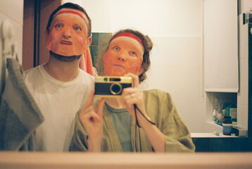 Couple making photo with face masks in a mirror 