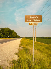 Brown road sign marker on the side of a rural road indicating Abraham Lincoln’s New Salem...