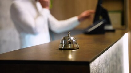 Guest ringing service bell at front desk, waiting to receive assistance from hotel staff at reception counter