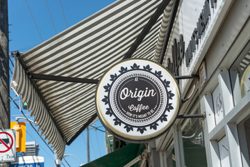 Fototapeta premium round projecting sign of At Origin Coffee, a coffee shop, with black and white sun awning located at 687 Mount Pleasant Road in Toronto, Canada
