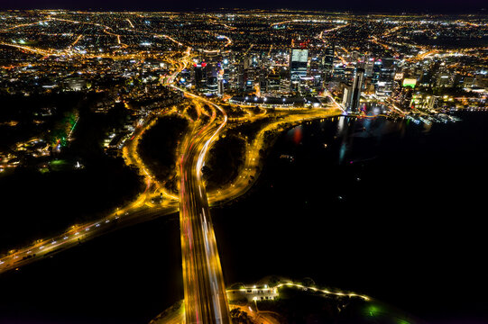 An aerial view of a bridge full leading to downtown at night