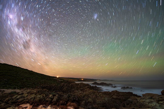 Colourful star trails over a beach shoreline