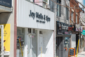 Fototapeta premium exterior building and sign of Joy Nails & Spa (and other nearby businesses) located at 290 Eglinton Avenue West in Toronto, Canada