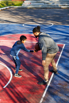 Son tackling father in basketball game at court