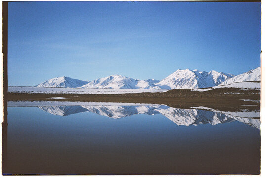 Film photo: Reflection of snowy mountains on lake
