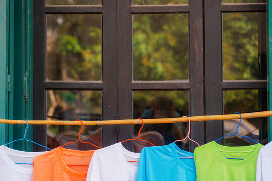 Colourful t-shirts drying on the hangers on backyard