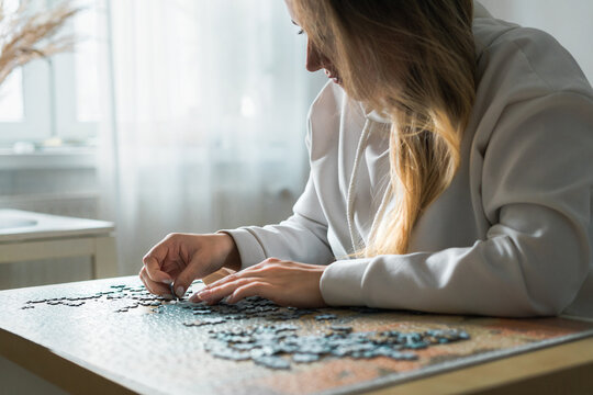 Young woman doing jigsaw puzzle at home