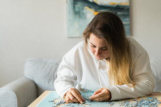 Young woman in assembling jigsaw puzzle at home