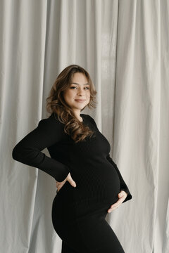 Pregnant Woman In Black Dress Touching Belly