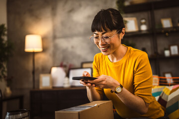 japanese woman checking box of received package or product at home