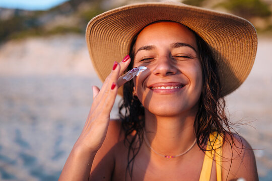 A Smiling Woman On the Beach Applying Sunscreen 